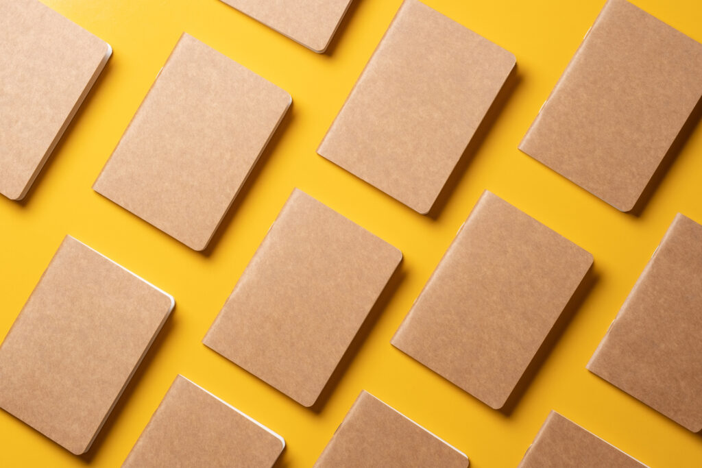 Pattern of brown craft paper notebooks on a yellow background.