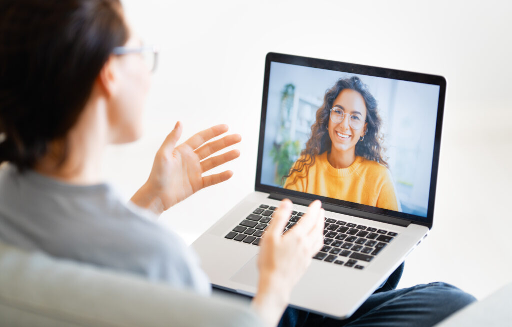 Young woman is using laptop for remote conversation with an accountability coach.