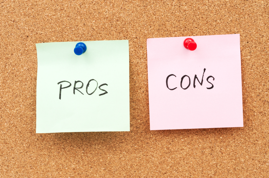 Sticky notes on a cork board reading "pro" and "con" representing the pros and cons of using an accountability coach.